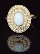 A c1910 9ct gold ring set with an oval opal cabochon surrounded by two rows of seed pearls, 5.8g,