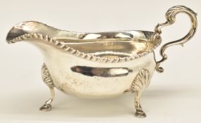 Georgian hallmarked silver sauce boat with gadrooned edge and raised on three feet, London 1818,