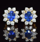 A pair of 18k gold earrings set with an oval sapphire of approximately 0.4ct surrounded by diamonds,