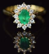 An 18ct gold ring set with an oval cut emerald of approximately 0.7ct and diamonds, 3.2g, size M
