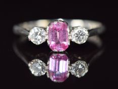 A platinum ring set with an emerald cut pink sapphire of approximately 0.7ct and two diamonds,