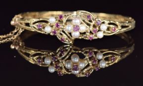 A 9ct gold bangle set with rubies and cultured pearls in a floral cluster, 16.5g, 4.7 x 5.7cm