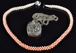 An Eastern white metal locket depicting a figure on a peacock and coral necklace with silver clasp