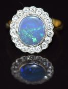 An 18ct gold ring set with an oval black opal cabochon surrounded by diamonds in a platinum setting,