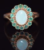 A 9ct gold ring set with an opal cabochon surrounded by emeralds, 4.4g, size U