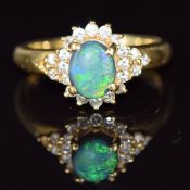 An 18ct gold ring set with a black opal cabochon surrounded by diamonds, 3.8g, size K