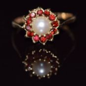 A 9ct gold ring set with a pearl surrounded by garnets, 2.5g, size O