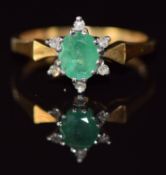 An 18ct gold ring set with an oval cut emerald and diamonds, 3.3g, size N/O