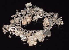 A silver charm bracelet with over twenty four charms including cherub, frog, fish, cat, elephant,