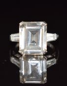 A 14k white gold ring set with an emerald cut white sapphire and baguette cut white topaz to each