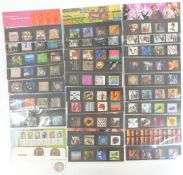 Twenty eight GB stamp presentation packs and three QEII £5 coins