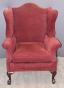 Victorian upholstered wing back armchair raised on ball and claw feet
