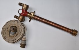 Vintage copper and brass fire hose standpipe with twin outlet top, together with a canvas fire hose