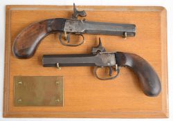 A pair of percussion hammer action pocket pistols each with shaped wooden grips and 3 inch smooth