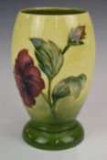 Moorcroft pedestal vase decorated in the Hibiscus pattern on yellow ground, with Moorcroft signature