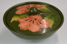 Moorcroft pedestal covered bowl decorated in the Hibiscus pattern on a green ground, H6 x D17cm