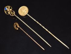 A 9ct gold horseshoe stick pin (0.6g), USA gold coin stick pin (2.6g) and gold plated example