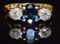 An 18ct gold ring set with an oval cut sapphire and two diamonds, 3.5g, size M