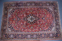 Large Persian carpet with central lozenge on a wine ground with navy border, 335 x 230cm