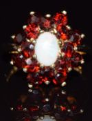 A 9ct gold ring set with an opal surrounded by garnets, 4.5g, size O