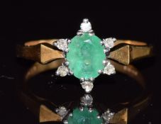 An 18ct gold ring set with an oval cut emerald and diamonds, 3.3g, size N/O