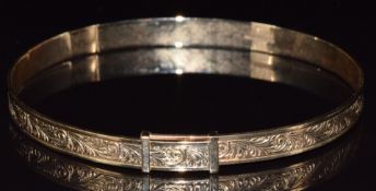 A 9ct gold bangle with scrolling decoration, 12.7g