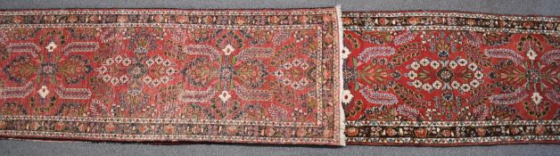 An exceptionally large wool runner with repeating floral design on a wine ground, 740cm x 90cm