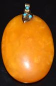 An amber pendant with 9ct gold snake shaped loop mount set with turquoise and a diamond, 23.9g