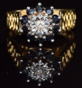 An 18ct ring set with a diamond surrounded by sapphires in a cluster setting, 6.1g, size Q