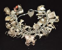 A silver charm bracelet with 26 silver charms including beer barrel opening to reveal a man