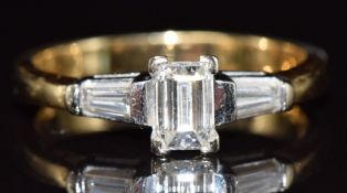 An 18ct gold ring set with an emerald cut diamond of approximately 0.6ct and a further baguette