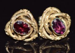 A pair of Victorian yellow metal knot earrings set with foiled garnets with engraved and textured