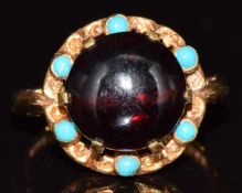 A 9ct gold ring set with a garnet cabochon surrounded by turquoise cabochons, 3.9g, size I
