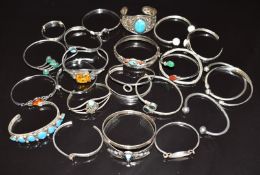 Twenty-five silver bangles including Navajo, pressed amber, etc