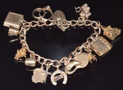 A 9ct gold charm bracelet with thirteen 9ct gold charms including pram opening to reveal a baby,