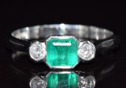 A platinum ring set with an octagonal emerald of approximately 0.65ct and two diamonds, each