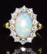 An 18ct gold ring set with an opal cabochon of approximately 1.8ct surrounded by diamonds, 6g,