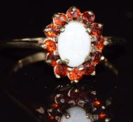 A 9ct gold ring set with an opal surrounded by garnets, 2.7g, size O