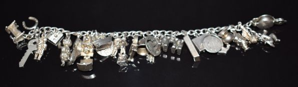 A silver charm bracelet with 26 silver charms including horseshoe, train, Noah's Ark opening to