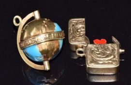 A 14ct gold charm in the form of a globe set with aqua blue enamel and text reading 'die ganze