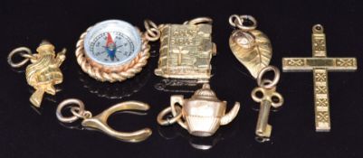 Eight 9ct gold charms/ pendants including compass, bible, cross, ladybird on leaf, key & wishbone,