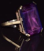 A 9ct gold ring set with an emerald cut synthetic purple sapphire, 11.8g, size M