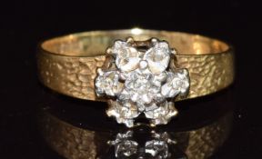 An 18ct gold ring set with diamonds in a cluster with textured shoulders, 2.9g, size Q