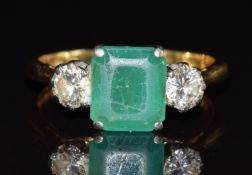 An 18ct gold ring set with an emerald cut emerald and two round cut diamonds, each approximately 0.