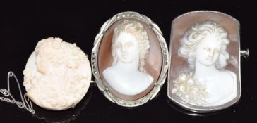 A silver brooch set with a coral cameo, and two silver brooches both set with cameos depicting young