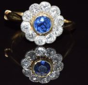 An 18ct gold ring set with a round cut sapphire of approximately 0.35ct surrounded by diamonds, each