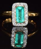 An 18ct gold ring set with an emerald cut emerald of approximately 0.8ct surrounded by diamonds, 5.