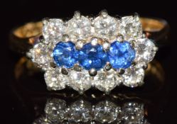 An 18ct gold ring set with three round cut sapphires surrounded by diamonds, each gemstone
