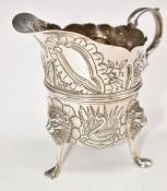 Victorian or Edward VII Irish hallmarked silver milk jug with embossed decoration, raised on three