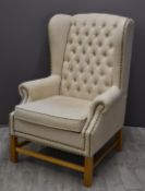 Contemporary wing backed upholstered armchair with button back and studded decoration, width 82cm